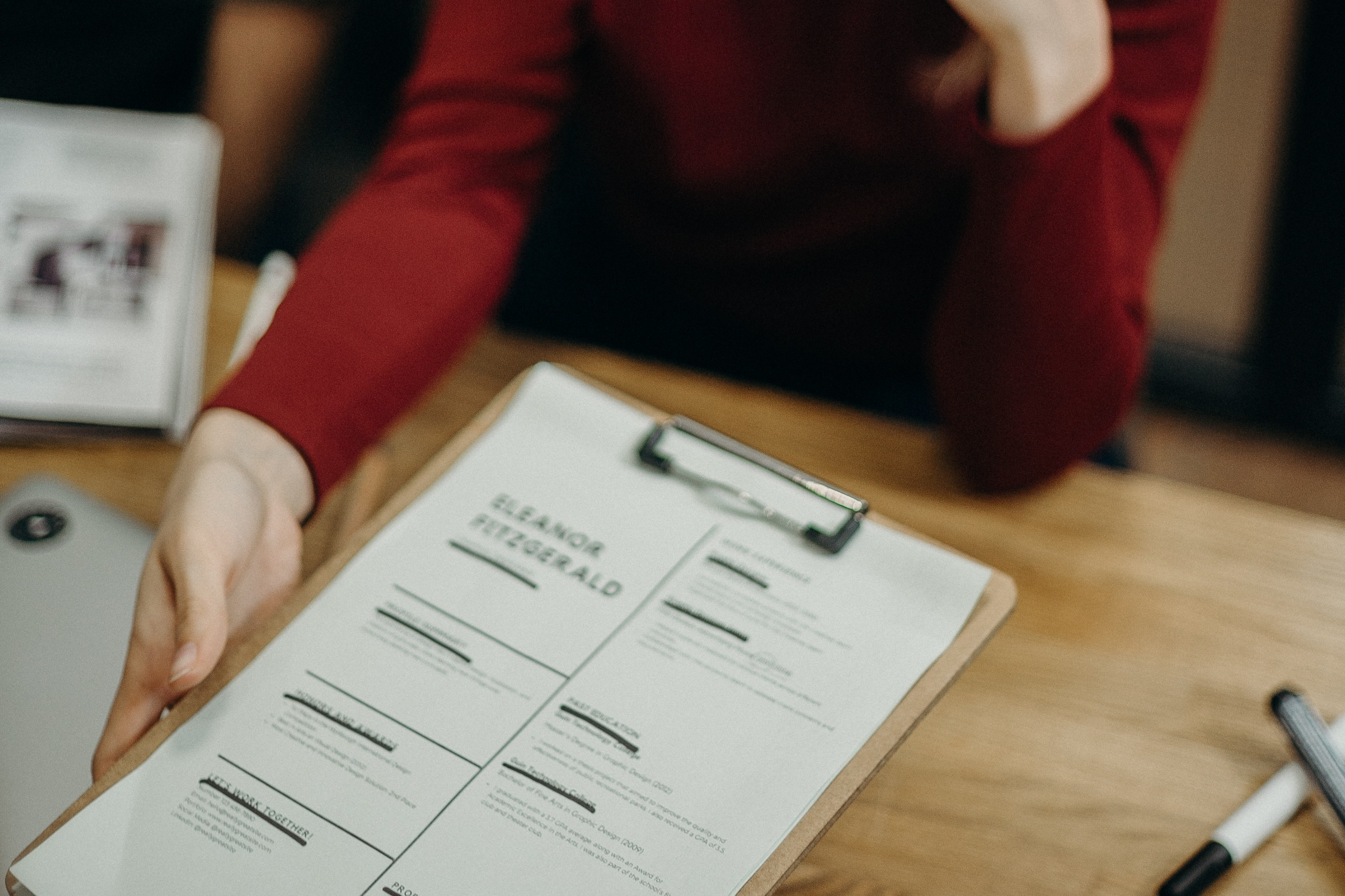 Close up of candidate handing their CV to a hiring manager. 